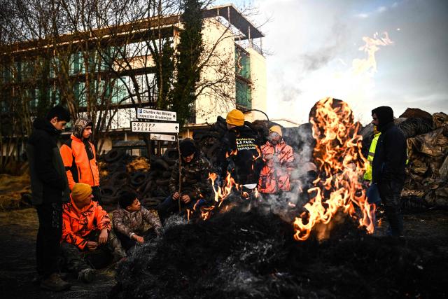 Farmers of the CR47 union (Coordination rurale 47) stand by a bonfire as they  protest outside the "Direction departementale de l'emploi, du travail, des solidarites et de la protection des populations" (Departmental Directorate of Employment, Labor, Social Affairs, and Population Protection) of Lot-et-Garonne in Agen, south-western France, on December 12, 2025. (Photo by Christophe ARCHAMBAULT / AFP)