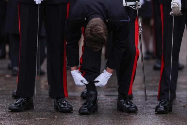 An officer cadet makes an adjustment to his uniform ahead of the traditional No. 251 Sovereign’s Parade, at the Royal Military Academy in Sandhurst, southwest of London on December 12, 2025. The parade marks the completion of 44 weeks of intensive training for the Officer Cadets of Commissioning Course 251. (Photo by Adrian Dennis / AFP)