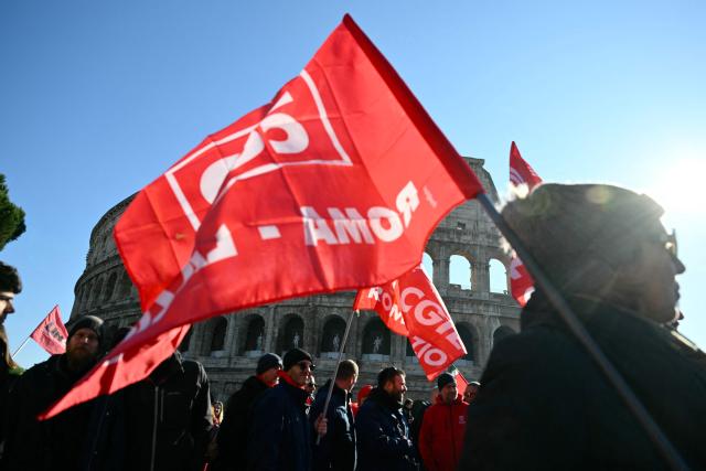 People march near the Colosseum during a national day of strike by Italian union "Confederazione Generale Italiana del Lavoro" (CGIL) against the government's budget law, on December 12, 2025. (Photo by Alberto PIZZOLI / AFP)