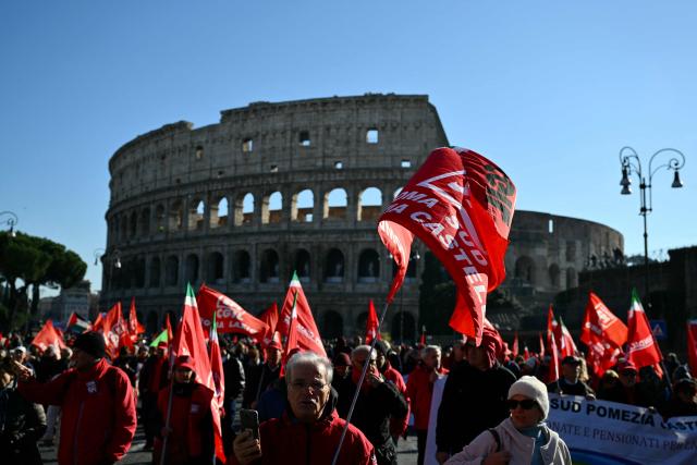 People march near the Colosseum during a national day of strike by Italian union "Confederazione Generale Italiana del Lavoro" (CGIL) against the government's budget law, on December 12, 2025. (Photo by Alberto PIZZOLI / AFP)