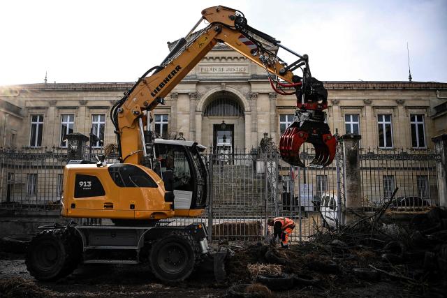 Municipal workers clear debris dumped overnight by farmers of the CR47 union (Coordination rurale 47) in front of the courthouse as part of a protest in Agen, south-western France, on December 12, 2025. (Photo by Christophe ARCHAMBAULT / AFP)