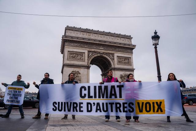 Activists hold a banner reading "Climate, follow other voices"  during a Greenpeace action in front of the Arc de Triomphe in Paris on December 12, 2025, marking the 10 year anniversary of the signing of the Paris Climate accords. (Photo by Dimitar DILKOFF / AFP)