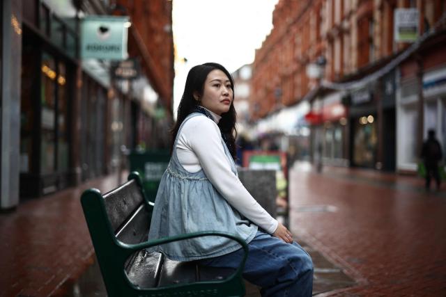 Carmen Lau, Hong Kong pro-democracy activist living in exile in the UK, poses for a photograph in the centre of Reading, west of London, on December 12, 2025. The Hong Kong activist living in exile in the UK said she was "shocked and terrified" after discovering her neighbours received letters containing AI-generated sexually explicit images of her. Lau, like several other high-profile Hong Kong refugees in the UK, found out first earlier this year that her neighbours had been sent letters encouraging them to turn her in to the Chinese embassy, offering rewards of tens of thousands of pounds. (Photo by Henry NICHOLLS / AFP)