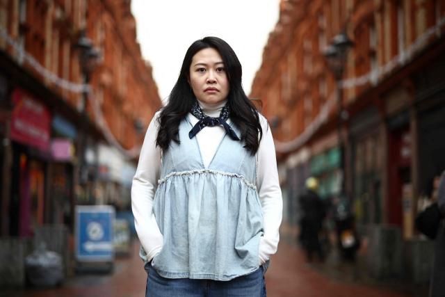 Carmen Lau, Hong Kong pro-democracy activist living in exile in the UK, poses for a photograph in the centre of Reading, west of London, on December 12, 2025. The Hong Kong activist living in exile in the UK said she was "shocked and terrified" after discovering her neighbours received letters containing AI-generated sexually explicit images of her. Lau, like several other high-profile Hong Kong refugees in the UK, found out first earlier this year that her neighbours had been sent letters encouraging them to turn her in to the Chinese embassy, offering rewards of tens of thousands of pounds. (Photo by Henry NICHOLLS / AFP)