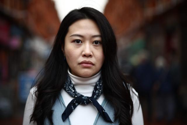 Carmen Lau, Hong Kong pro-democracy activist living in exile in the UK, poses for a photograph in the centre of Reading, west of London, on December 12, 2025. The Hong Kong activist living in exile in the UK said she was "shocked and terrified" after discovering her neighbours received letters containing AI-generated sexually explicit images of her. Lau, like several other high-profile Hong Kong refugees in the UK, found out first earlier this year that her neighbours had been sent letters encouraging them to turn her in to the Chinese embassy, offering rewards of tens of thousands of pounds. (Photo by HENRY NICHOLLS / AFP)