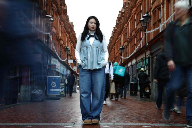 Carmen Lau, Hong Kong pro-democracy activist living in exile in the UK, poses for a photograph in the centre of Reading, west of London, on December 12, 2025. The Hong Kong activist living in exile in the UK said she was "shocked and terrified" after discovering her neighbours received letters containing AI-generated sexually explicit images of her. Lau, like several other high-profile Hong Kong refugees in the UK, found out first earlier this year that her neighbours had been sent letters encouraging them to turn her in to the Chinese embassy, offering rewards of tens of thousands of pounds. (Photo by HENRY NICHOLLS / AFP)