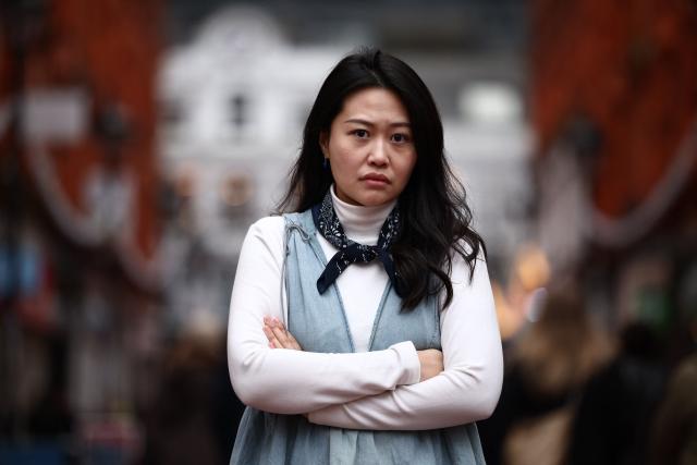 Carmen Lau, Hong Kong pro-democracy activist living in exile in the UK, poses for a photograph in the centre of Reading, west of London, on December 12, 2025. The Hong Kong activist living in exile in the UK said she was "shocked and terrified" after discovering her neighbours received letters containing AI-generated sexually explicit images of her. Lau, like several other high-profile Hong Kong refugees in the UK, found out first earlier this year that her neighbours had been sent letters encouraging them to turn her in to the Chinese embassy, offering rewards of tens of thousands of pounds. (Photo by HENRY NICHOLLS / AFP)