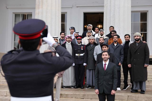 UAE officer cadet Almansoori (C) poses photo a photo on the steps with extended family as he takes part in the No. 251 Sovereign’s Parade ceremonies at the Royal Military Academy in Sandhurst, southwest of London on December 12, 2025. The parade marks the completion of 44 weeks of intensive training for the Officer Cadets of Commissioning Course 251. (Photo by Adrian DENNIS / AFP)
