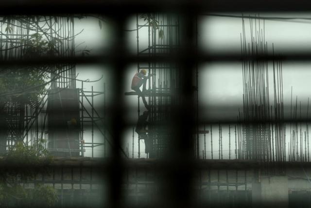 Workers get down from scaffolding at an under-construction site on a smoggy afternoon in Varanasi on December 12, 2025. (Photo by Niharika KULKARNI / AFP)