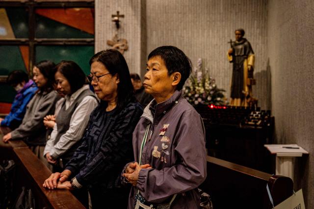 People pray during a Mass at the St. Benedict's Church in Hong Kong on December 12, 2025, for the victims of a deadly fire at the Wang Fuk Court residential estate in the Tai Po district. (Photo by Leung Man Hei / AFP)