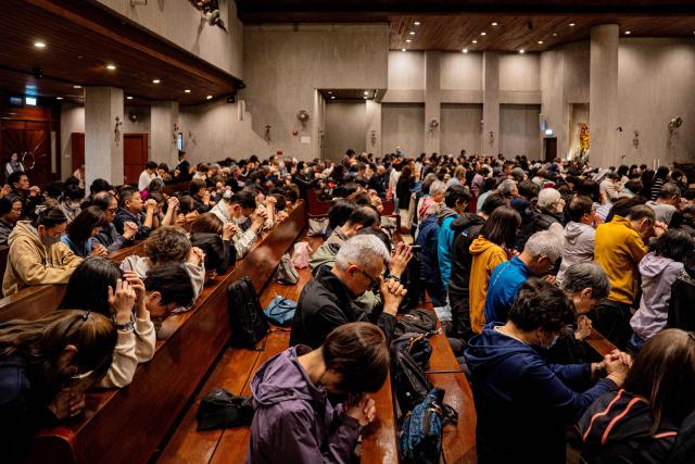 People pray during a Mass at the St. Benedict's Church in Hong Kong on December 12, 2025, for the victims of a deadly fire at the Wang Fuk Court residential estate in the Tai Po district. (Photo by Leung Man Hei / AFP)
