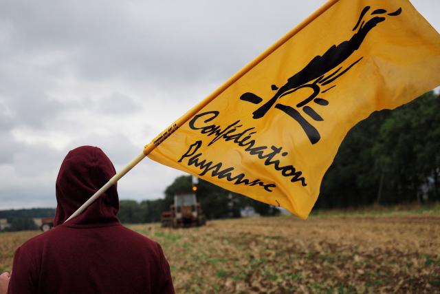 (FILES) A member of French farmers union La Confederation Paysanne stands with a flag as they occupate fields belonging to Chinese farmers, during a demonstration against "land grabbing" by Chinese investors, in Murs, near Chatillon-sur-Indre on August 29, 2018. On December 12, the Confйdйration paysanne farmer union is calling for “blockades across France” to protest the government’s approach to contagious nodular dermatitis (CND), as the latter considers the “slaughter” of cattle infected with the disease to be “the only solution” to “save the industry". (Photo by GUILLAUME SOUVANT / AFP)