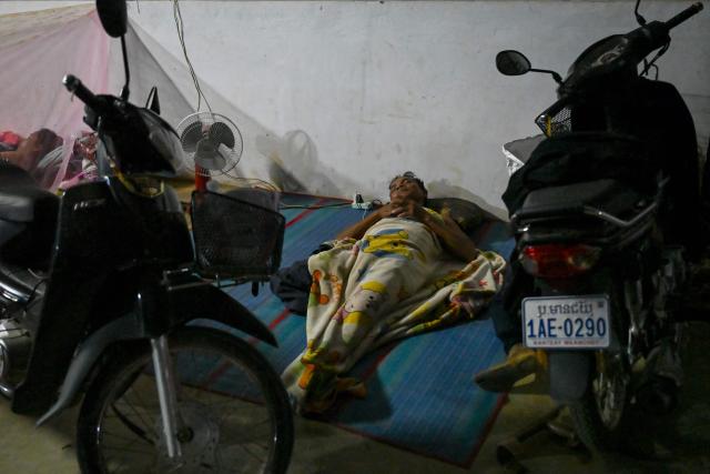 A displaced resident sleeps at a temporary camp in Banteay Meanchey province on December 12, 2025, amid clashes along the Cambodia-Thailand border. (Photo by TANG CHHIN Sothy / AFP)