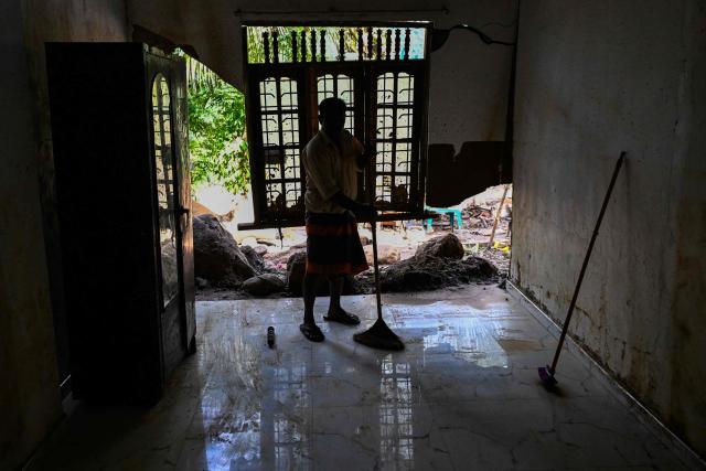 A resident removes mud from a house following flash floods in the aftermath of Cyclone Ditwah, in Badulla on December 12, 2025. Two tropical storms dumped massive amounts of rain on the countries last month, prompting landslides and flooding that killed more than 600 people in Sri Lanka and nearly 1,000 in Indonesia. (Photo by Ishara S. KODIKARA / AFP)