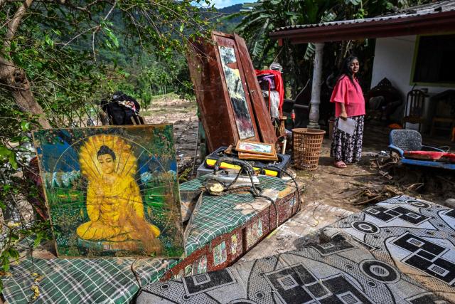 A resident stands next to her belongings following flash floods in the aftermath of Cyclone Ditwah, in Badulla on December 12, 2025. Two tropical storms dumped massive amounts of rain on the countries last month, prompting landslides and flooding that killed more than 600 people in Sri Lanka and nearly 1,000 in Indonesia. (Photo by Ishara S. KODIKARA / AFP)