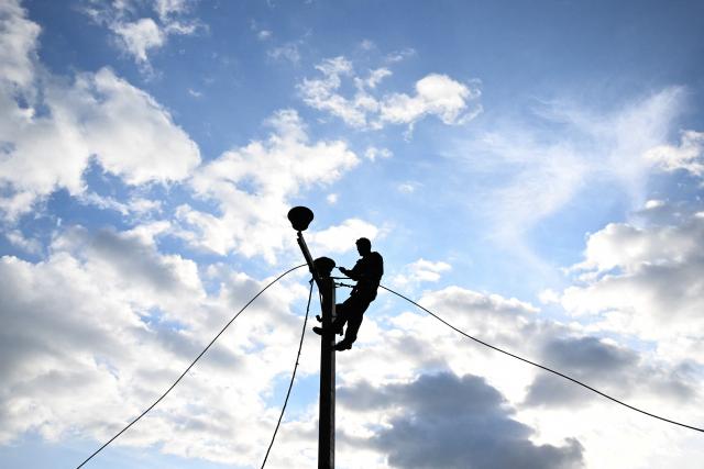 A Lanka Electricity Company (LECO) worker carries out maintenance work on an electric pole near a landslide-affected area in the aftermath of Cyclone Ditwah, in Badulla on December 12, 2025. Two tropical storms dumped massive amounts of rain on the countries last month, prompting landslides and flooding that killed more than 600 people in Sri Lanka and nearly 1,000 in Indonesia. (Photo by Ishara S. KODIKARA / AFP)