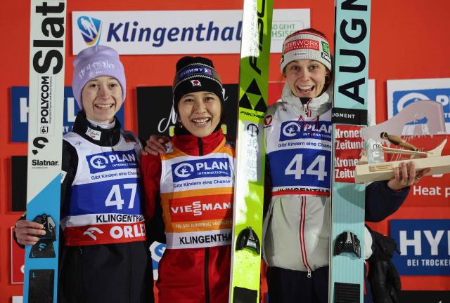 (L-R) Slovenia's Nika Prevc (2nd), winner Japan's Nozomi Maruyama and Austria's Lisa Eder (3rd) celebrate on the podium after the women's Individual Large Hill HS140 event of the FIS Ski Jumping World Cup in Klingenthal, eastern Germany on December 12, 2025. Japan's Nozomi Maruyama won the event ahead of Slovenia's Nika Prevc (2nd) and . (Photo by JENS SCHLUETER / AFP)