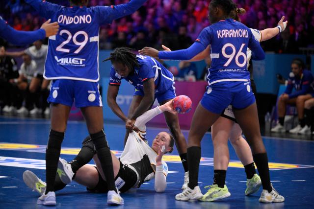 Germany's left back #19 Nieke Kuhne (floor) fights for the ball with France's centre back #02 Meline Nocandy during the IHF Women's Handball World Championship semi final match between France and Germany in Rotterdam Ahoy Arena, in Rotterdam, on December 12, 2025. (Photo by JOHN THYS / AFP)