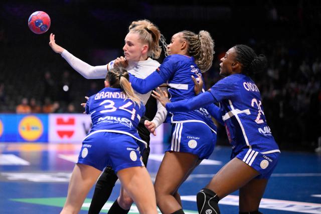 Germany's centre back #23 Annika Lott (2L) passes the ball as she is challenged by France's centre back #34 Lena Grandveau (L), France's right back #15 Marie-Helene Sajka (2R) and France's pivot #29 Oriane Ondono (R) during the IHF Women's Handball World Championship semi final match between France and Germany in Rotterdam Ahoy Arena, in Rotterdam, on December 12, 2025. (Photo by JOHN THYS / AFP)