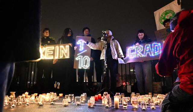 Greenpeace environmental activists stage an action with illuminated placards reading "Not a tenth of a degree further" to mark the 10th anniversary of the signing of the Paris Climate agreements, on December 12, 2025 in Vienna. (Photo by Joe Klamar / AFP)