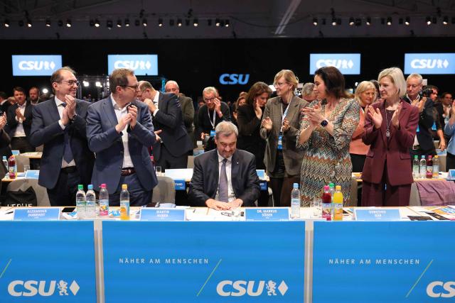(From L) Germany's Interior Minister and member of the Bavarian conservative Christian Social Union (CSU) party Alexander Dobrindt, General Secretary of the Bavarian conservative Christian Social Union (CSU) party Martin Huber, German Minister for Research, Technology and Aerospace Dorothee Baer and other CSU delegates applaud Bavaria's State Premier and leader of the conservative Christian Social Union (CSU) Markus Soeder (C) after he was reelected  during a congress of the Christian Social Union (CSU) party on December 12, 2025 in Munich, southern Germany. Soeder has been confirmed in office with only 83.6 percent approval, his worst result to date at the CSU party conference in Munich. In the last election two years ago, Soeder won 96.6 percent of the delegate votes. (Photo by Alexandra BEIER / AFP)