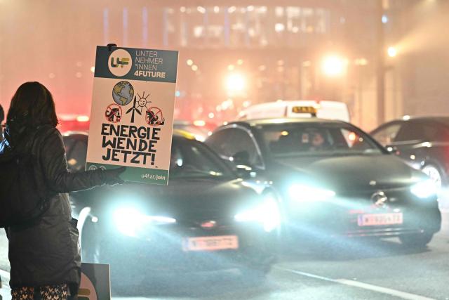 Environmental activists stage an action holding a placard reading "Energy transition now!" to mark the 10th anniversary of the signing of the Paris Climate agreements, on December 12, 2025 in Vienna, Austria. (Photo by Joe Klamar / AFP)