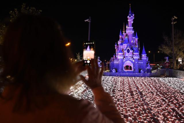 A woman takes picture of Christmas illumination in Furiani on the French Mediterranean island of Corsica, on December 12, 2025. (Photo by Pascal POCHARD-CASABIANCA / AFP)