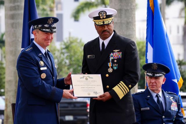 US Air Force Gen. Dan Caine (L), chairman of the Joint Chiefs of Staff, presents a plaque to US Navy Adm. Alvin Holsey (R) during Holsey’s relinquishment of command and retirement ceremony at US Southern Command (SOUTHCOM) headquarters in Doral, Florida, on December 12, 2025. The US admiral responsible for overseeing a major military buildup in the Caribbean and controversial strikes on alleged drug-smuggling boats stepped down on Friday just a year into his tenure. (Photo by Eva Marie UZCATEGUI / AFP)
