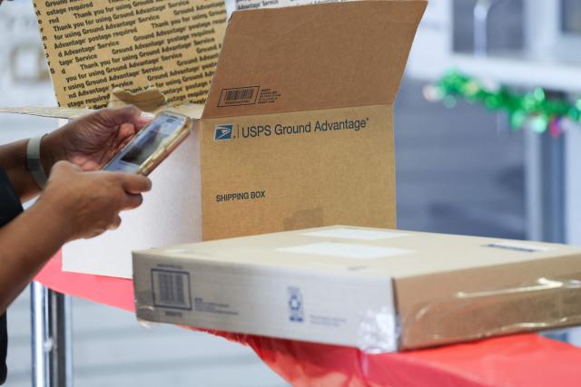 A customer waits to mail packages ahead of holiday shipping deadlines at the United States Postal Service (USPS) Gardena Post Office in Gardena, California, on December 12, 2025. The USPS reported an increase in expanded daily processing capacity from 60 million to 88 million packages nationwide by deploying more than 600 package sorters, with over 6 billion pieces of mail and packages accepted this holiday season. (Photo by Patrick T. Fallon / AFP)