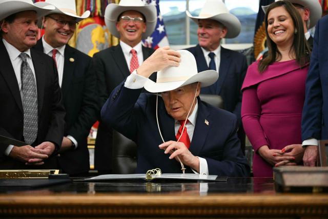 US President Donald Trump puts on a cowboy hat during a bill signing ceremony with members of the 1980 US Olympic men's ice hockey team in the Oval Office of the White House in Washington, DC, on December 12, 2025. The legislation will award all of the players with Congressional Gold Medals to recognize the 45th anniversary of the US victory at the 1980 Winter Olympic Games. (Photo by Jim WATSON / AFP)