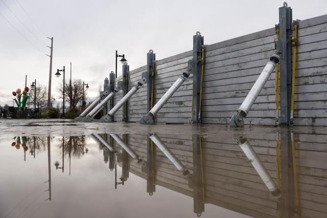 A flood wall is up along the Skagit River in Mount Vernon, Washington, on December 12, 2025. Tens of thousands of people were under evacuation orders on December 11 in western North America, after days of heavy rain forced rivers to burst their banks. Storms have battered Washington state in the US and British Columbia over the Canadian border for several days, with rivers continuing to rise. (Photo by Jason Redmond / AFP)