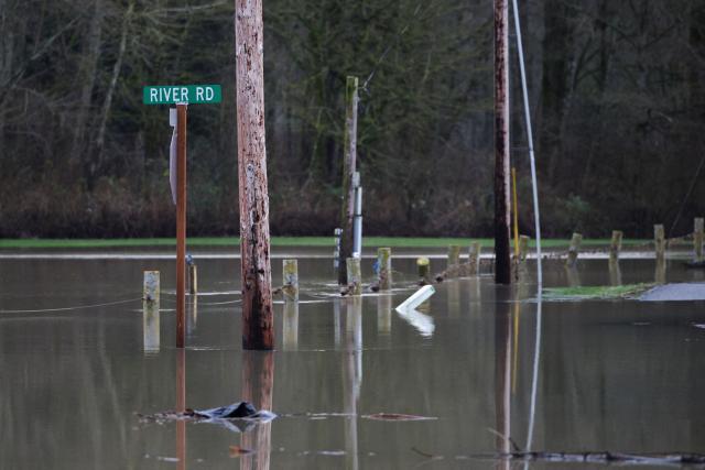 A street sign is surrounded by flood waters from the Skagit River in Sedro-Woolley, Washington, on December 12, 2025. Tens of thousands of people were under evacuation orders on December 11 in western North America, after days of heavy rain forced rivers to burst their banks. Storms have battered Washington state in the US and British Columbia over the Canadian border for several days, with rivers continuing to rise. (Photo by Jason Redmond / AFP)