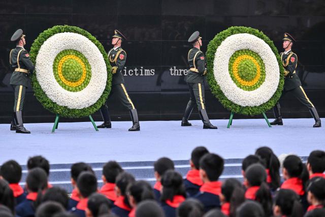 Honour guards place floral tributes during a ceremony to mark China's National Memorial Day for Nanjing Massacre Victims in Nanjing, in China's eastern Jiangsu province on December 13, 2025. (Photo by Hector RETAMAL / AFP)