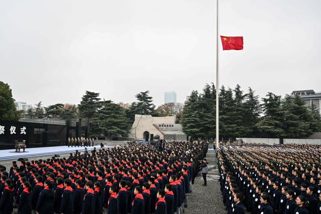 The Chinese flag is flown at half mast during a ceremony to mark China's National Memorial Day for Nanjing Massacre Victims in Nanjing, in China's eastern Jiangsu province on December 13, 2025. (Photo by Hector RETAMAL / AFP)