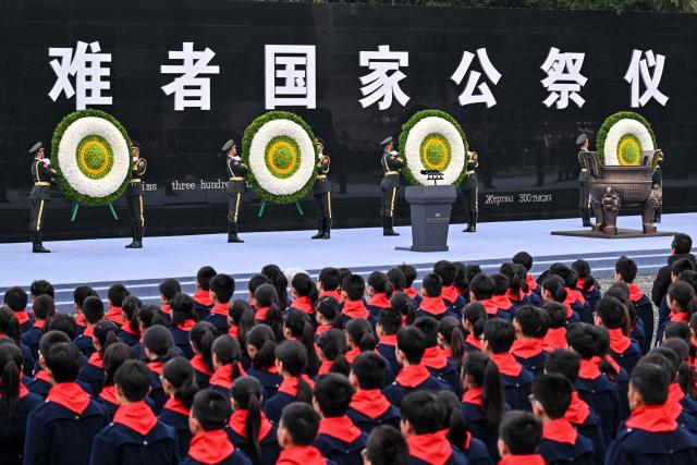 Honor guards place floral tributes during a ceremony to mark China's National Memorial Day for Nanjing Massacre Victims in Nanjing, in China's eastern Jiangsu province on December 13, 2025. (Photo by Hector RETAMAL / AFP)