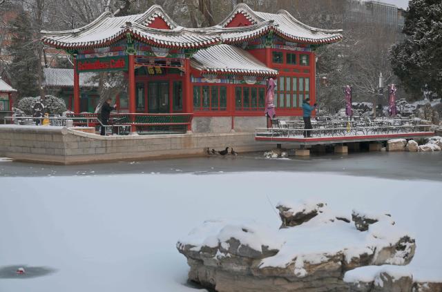 People take pictures in Ritan park one day after a heavy snowfall in Beijing on December 13, 2025. (Photo by Adek BERRY / AFP)