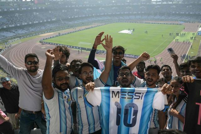 Fans of Argentinian football star Lionel Messi cheer from the stands before his arrival during the GOAT India Tour 2025 at the Salt Lake Stadium in Kolkata on December 13, 2025. Messi will unveil a 21-metre (70-foot) statue of himself in India on December 13, as he embarks on a three-day tour of the country that has sparked a fan frenzy. (Photo by Dibyangshu SARKAR / AFP)