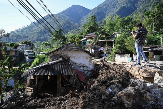 A man takes visuals of a damaged house after landslides in Passara on December 13, 2025. Tropical storms and monsoon rains have pummelled Southeast and South Asia in December, triggering landslides and flash floods that killed at least 639 people in Sri Lanka and nearly 1,000 in Indonesia. (Photo by Ishara S. KODIKARA / AFP)