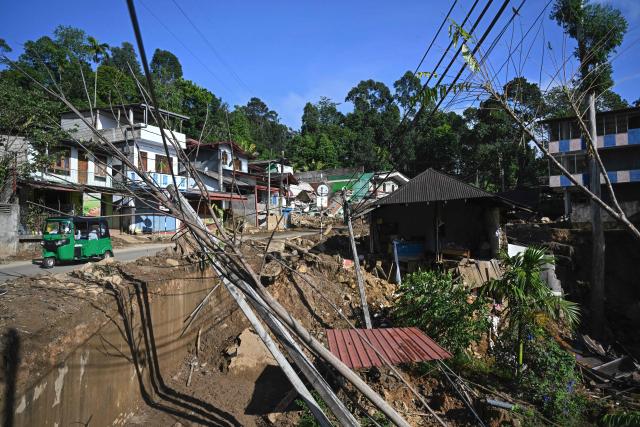 An auto-rickshaw driver rides past the wreckage along a roadside in the aftermath of landslides in Passara on December 13, 2025. Tropical storms and monsoon rains have pummelled Southeast and South Asia in December, triggering landslides and flash floods that killed at least 639 people in Sri Lanka and nearly 1,000 in Indonesia. (Photo by Ishara S. KODIKARA / AFP)
