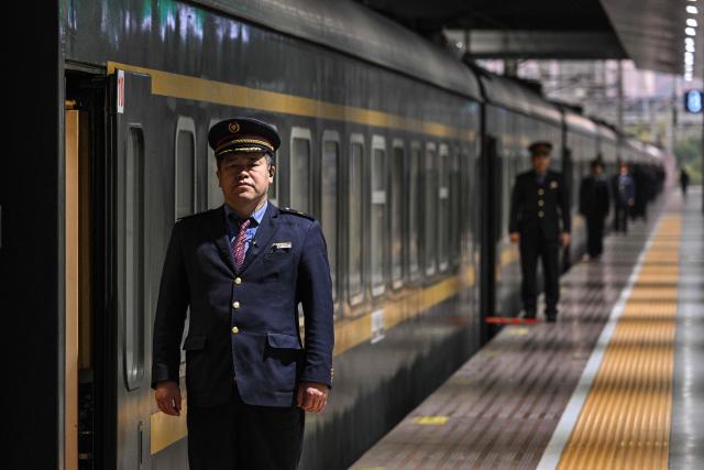 A staff member waits for passengers next to a train sleeping car at Shanghai Railway Station in Shanghai on December 13, 2025. (Photo by Hector RETAMAL / AFP)