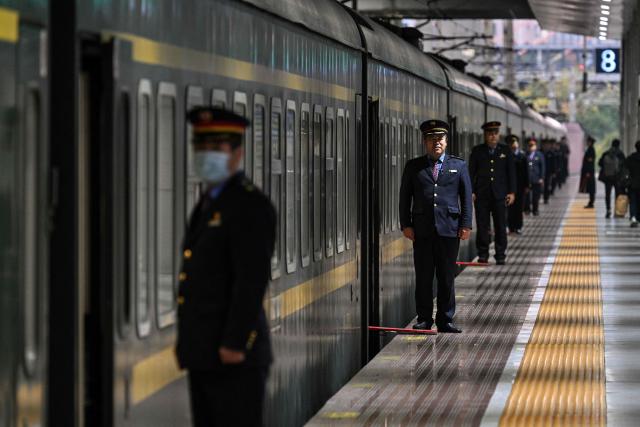 Staff members wait for passengers next to a train sleeping car at Shanghai Railway Station in Shanghai on December 13, 2025. (Photo by Hector RETAMAL / AFP)