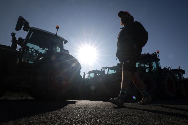 A farmer walks past tractors blocking the access to the A64 motorway, in Carbonne, south-western France, on December 13, 2025. On December 12, 2025 French veterinarians slaughtered a herd of cows thought to be diseased after police dispersed angry farmers trying to protect them, an AFP reporter said, as an agricultural union called for nationwide protests. French farmers are unhappy with the state's management of an outbreak of nodular dermatitis -- widely known as lumpy skin disease. (Photo by Valentine CHAPUIS / AFP)