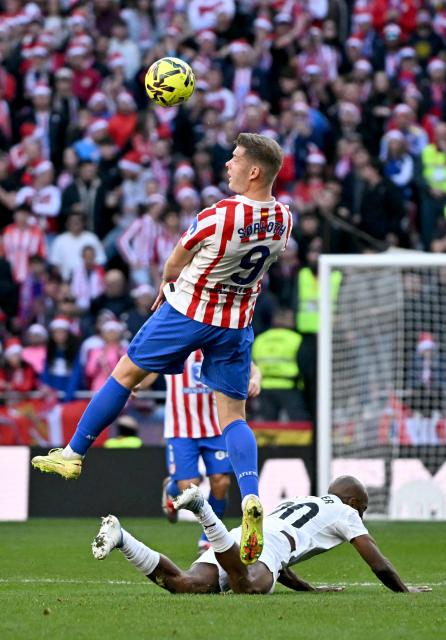 Atletico Madrid's Norwegian forward #09 Alexander Sorloth jumps for the ball next to Valencia's French defender # 20 Dimitri Foulquier during the Spanish league football match between Club Atletico de Madrid and Valencia CF at Metropolitano Stadium in Madrid on December 13, 2025. (Photo by Javier SORIANO / AFP)