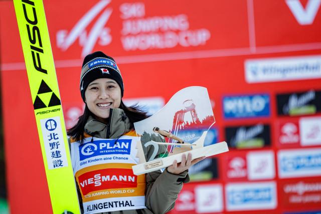 TOPSHOT - Second placed Japan's Nozomi Maruyama celebrates on the podium after winning in the Women's Individual Large Hill HS140 event of the FIS Ski Jumping World Cup in Klingenthal, eastern Germany on December 13, 2025. (Photo by JENS SCHLUETER / AFP)