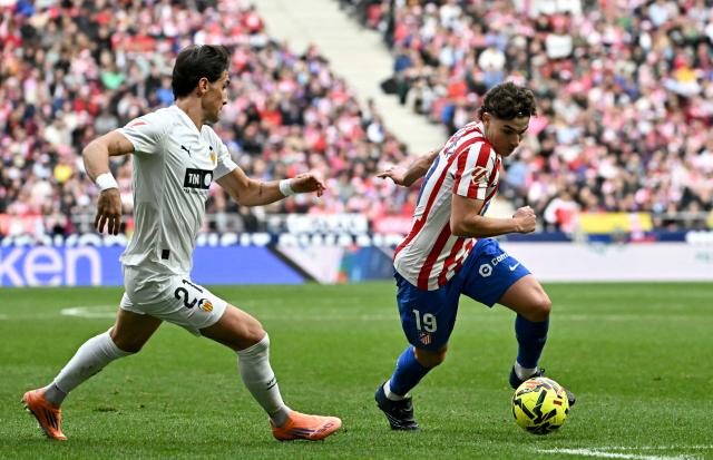 Atletico Madrid's Argentine forward #19 Julian Alvarez fights for the ball with Valencia's Spanish defender # 21 Jesus Vazquez during the Spanish league football match between Club Atletico de Madrid and Valencia CF at Metropolitano Stadium in Madrid on December 13, 2025. (Photo by Javier SORIANO / AFP)