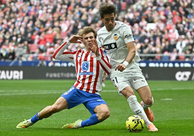 Atletico Madrid's Spanish midfielder #08 Pablo Barrios fights for the ball with Valencia's Spanish defender # 21 Jesus Vazquez during the Spanish league football match between Club Atletico de Madrid and Valencia CF at Metropolitano Stadium in Madrid on December 13, 2025. (Photo by Javier SORIANO / AFP)