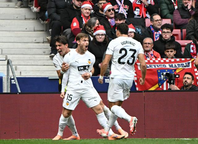 Valencia's Argentinian forward # 15 Lucas Beltran (2L) celebrates scoring his team's first goal in spite of Atletico Madrid's Slovenian goalkeeper #13 Jan Oblak during the Spanish league football match between Club Atletico de Madrid and Valencia CF at Metropolitano Stadium in Madrid on December 13, 2025. (Photo by Javier SORIANO / AFP)