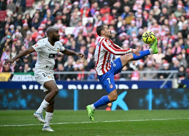 TOPSHOT - Atletico Madrid's French forward #07 Antoine Griezmann prepares to score his team's second goal next to Valencia's French defender # 20 Dimitri Foulquier during the Spanish league football match between Club Atletico de Madrid and Valencia CF at Metropolitano Stadium in Madrid on December 13, 2025. (Photo by Javier SORIANO / AFP)