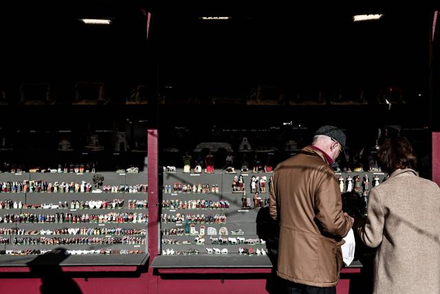 Pedestrians look at traditional Provencal santon small hand-painted terracotta figurines representing the Christmas nativity scene, traditional in the Provence region, on display at a stand at "La Foire aux Santons" (the Santons' fair) at the Vieux Port in Marseille, southeastern France on December 13, 2025. Santons are small, hand-painted terracotta figurines representing the traditional Provencal Christmas nativity scene. (Photo by Thibaud MORITZ / AFP)