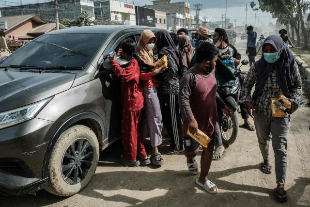 People affected by a flash flood receive food materials donated from a vehicle in Aceh Tamiang, Northern Sumatra, on December 13, 2025. Devastating floods and landslides have killed 1,006 people in Indonesia, rescuers said December 13 as the Southeast Asian nation grapples with the huge scale of relief efforts. (Photo by Yasuyoshi CHIBA / AFP)